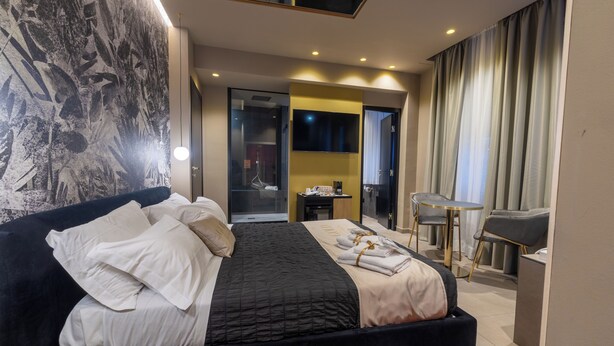 A modern hotel room with a large bed, a desk, and a seating area. - GOLD SUITE&SPA (Palermo)