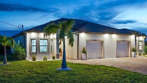 Ein modernes, zweistöckiges Haus mit Garage, gepflegtem Rasen und einer Palme.
