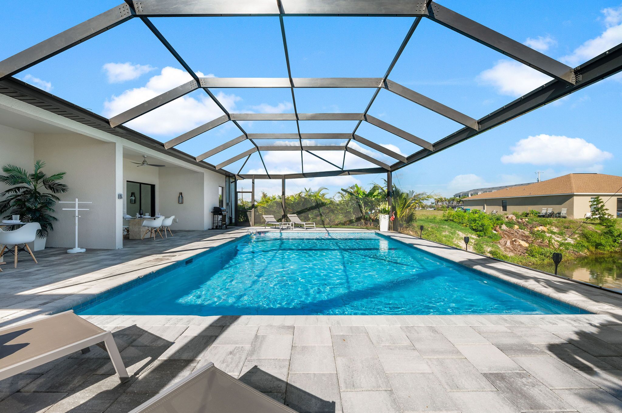 Une piscine dotée d’un toit en verre, entourée de chaises longues et d’un espace patio.