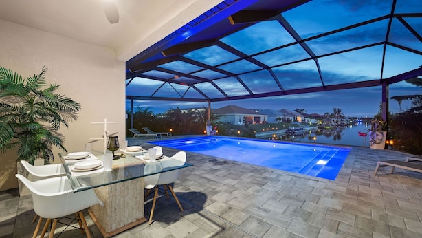 Ein Außenpoolbereich mit Glasveranda, einem Esstisch mit Stühlen und Blick auf die umliegende Landschaft.