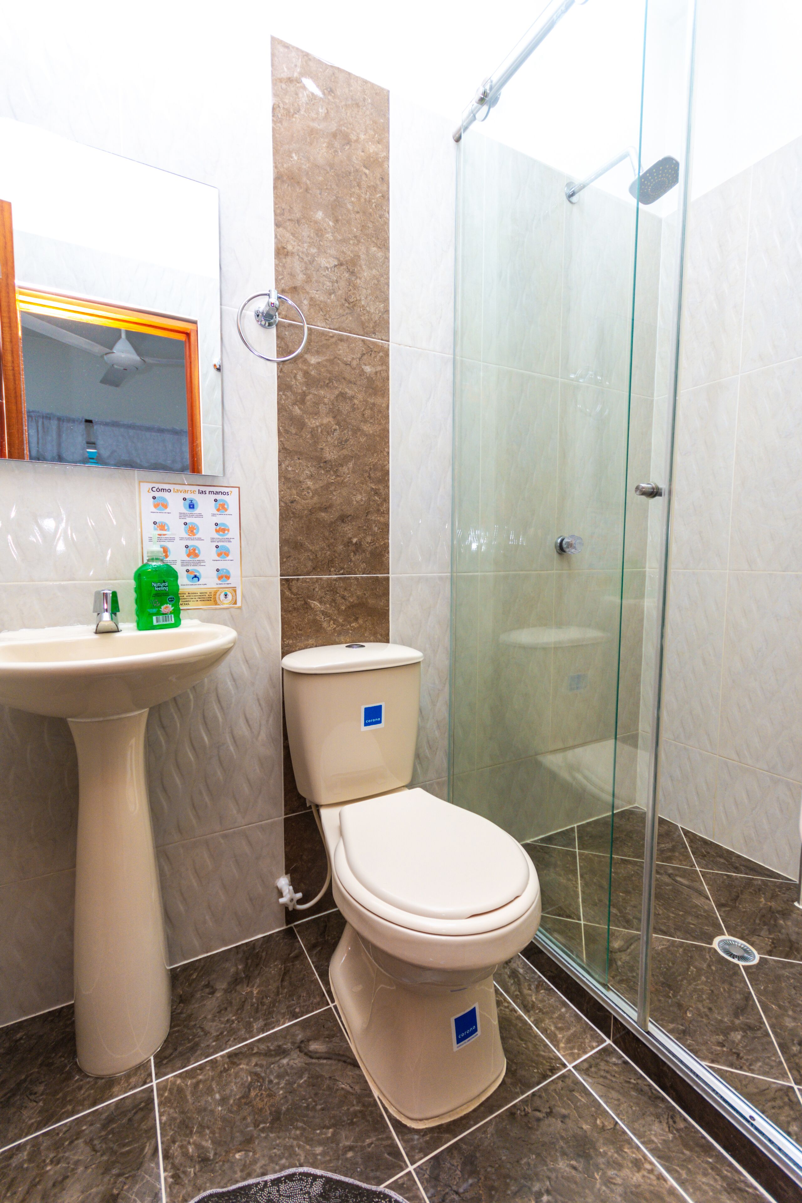 Een badkamer met een wastafel op een zuil, een toilet en een douchecabine.