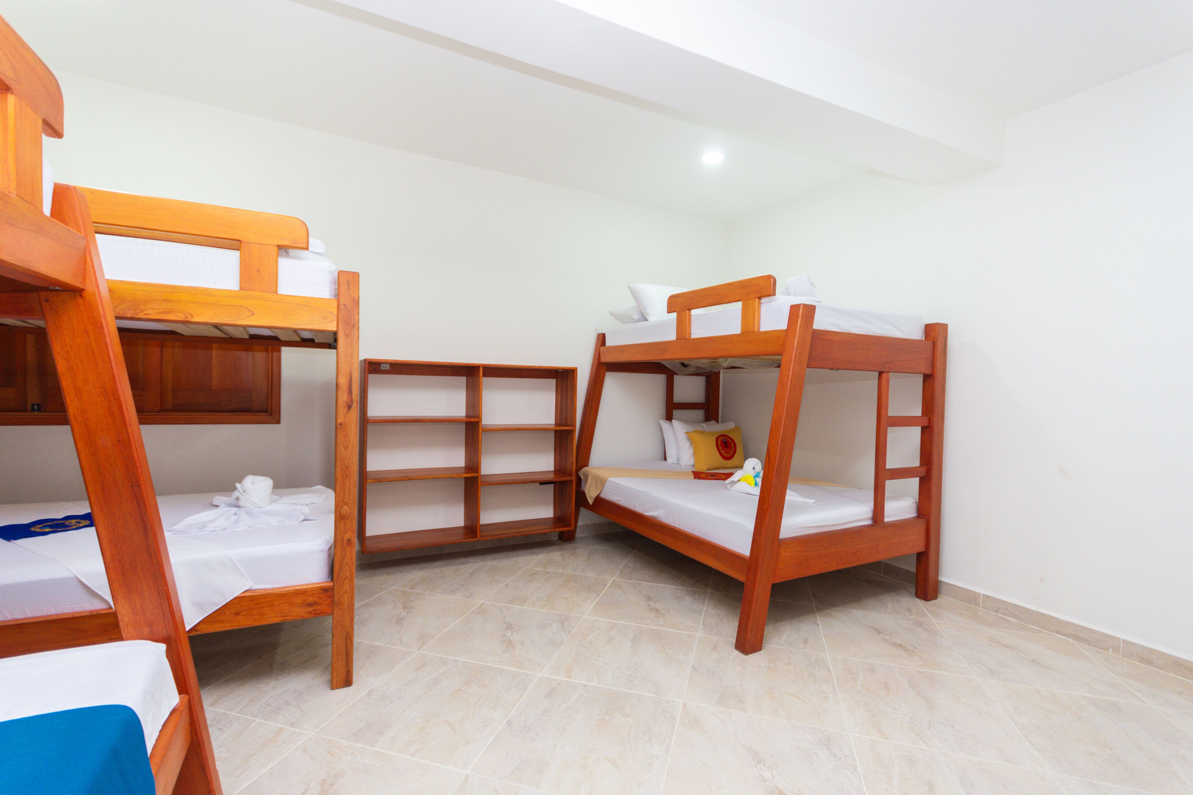 A room with bunk beds, a wooden shelf unit, and a tiled floor.