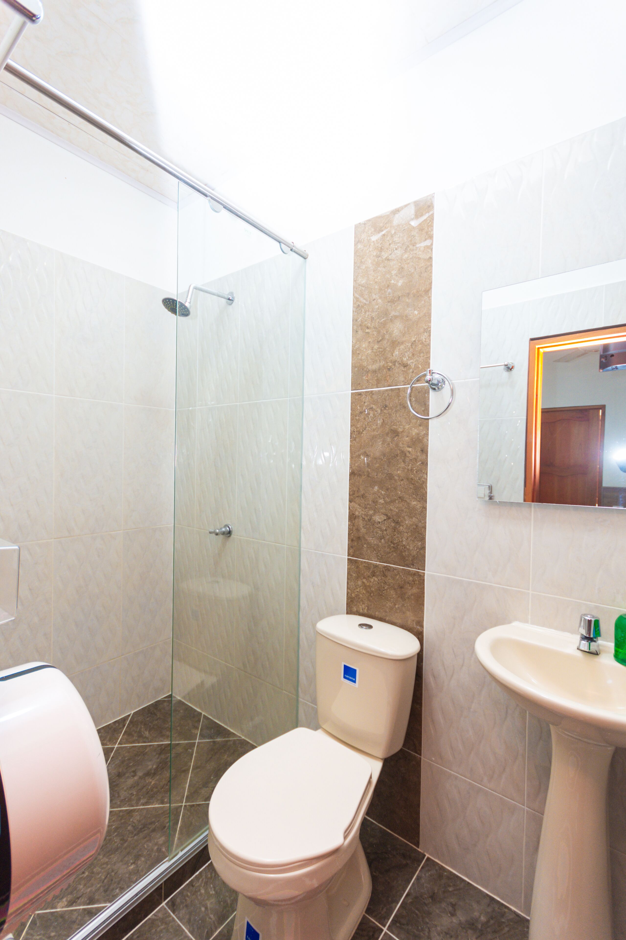 Une salle de bain avec une douche à parois de verre, des toilettes et un lavabo.
