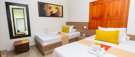 Habitación de hotel con dos camas individuales, cabecera de madera, un espejo grande y un cuadro en la pared.