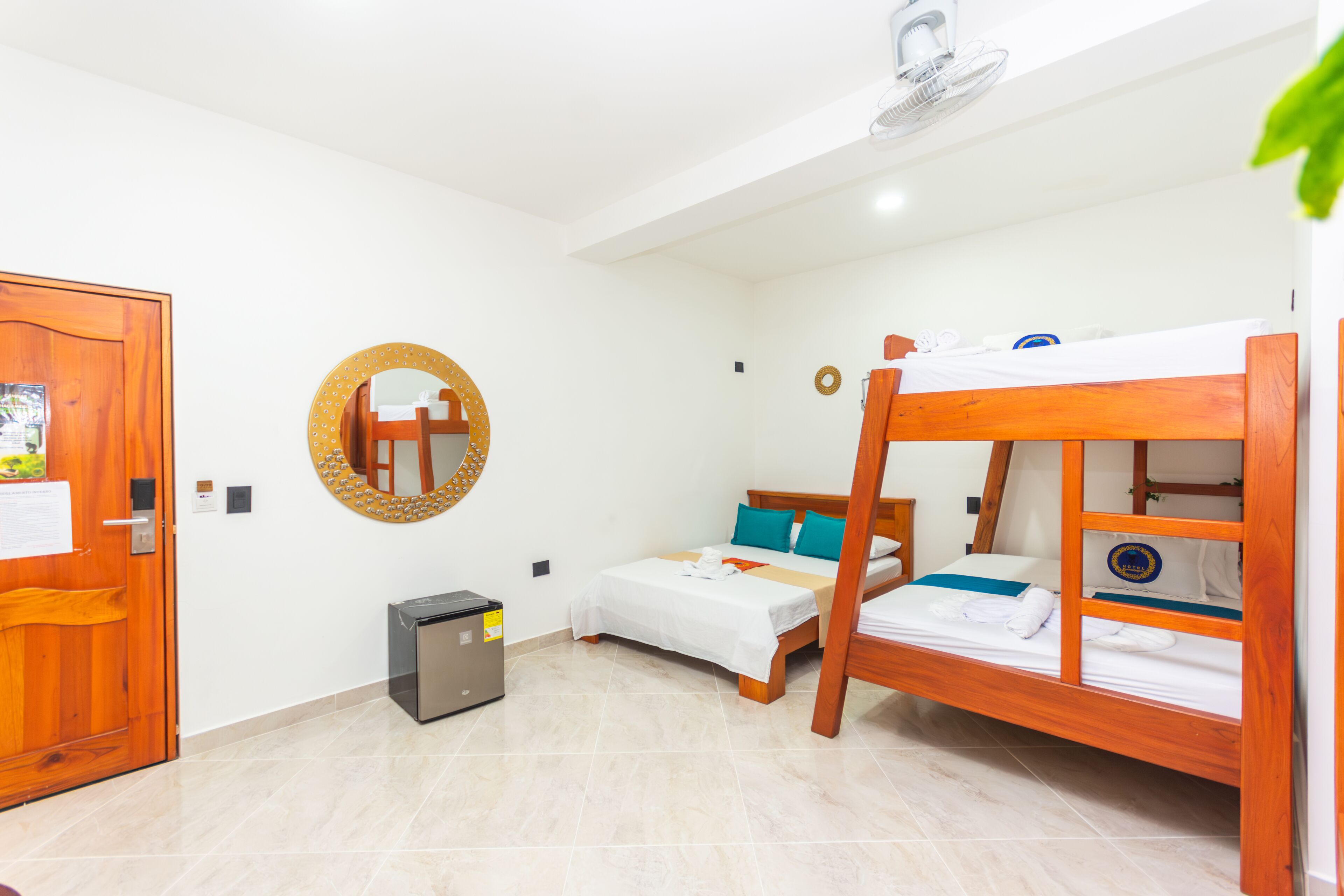 A room with a bunk bed, a small desk, a mirror, and a door.