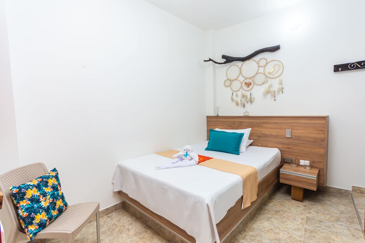 Une chambre d’hôtel avec un lit, une table de chevet, une chaise et un élément décoratif mural.