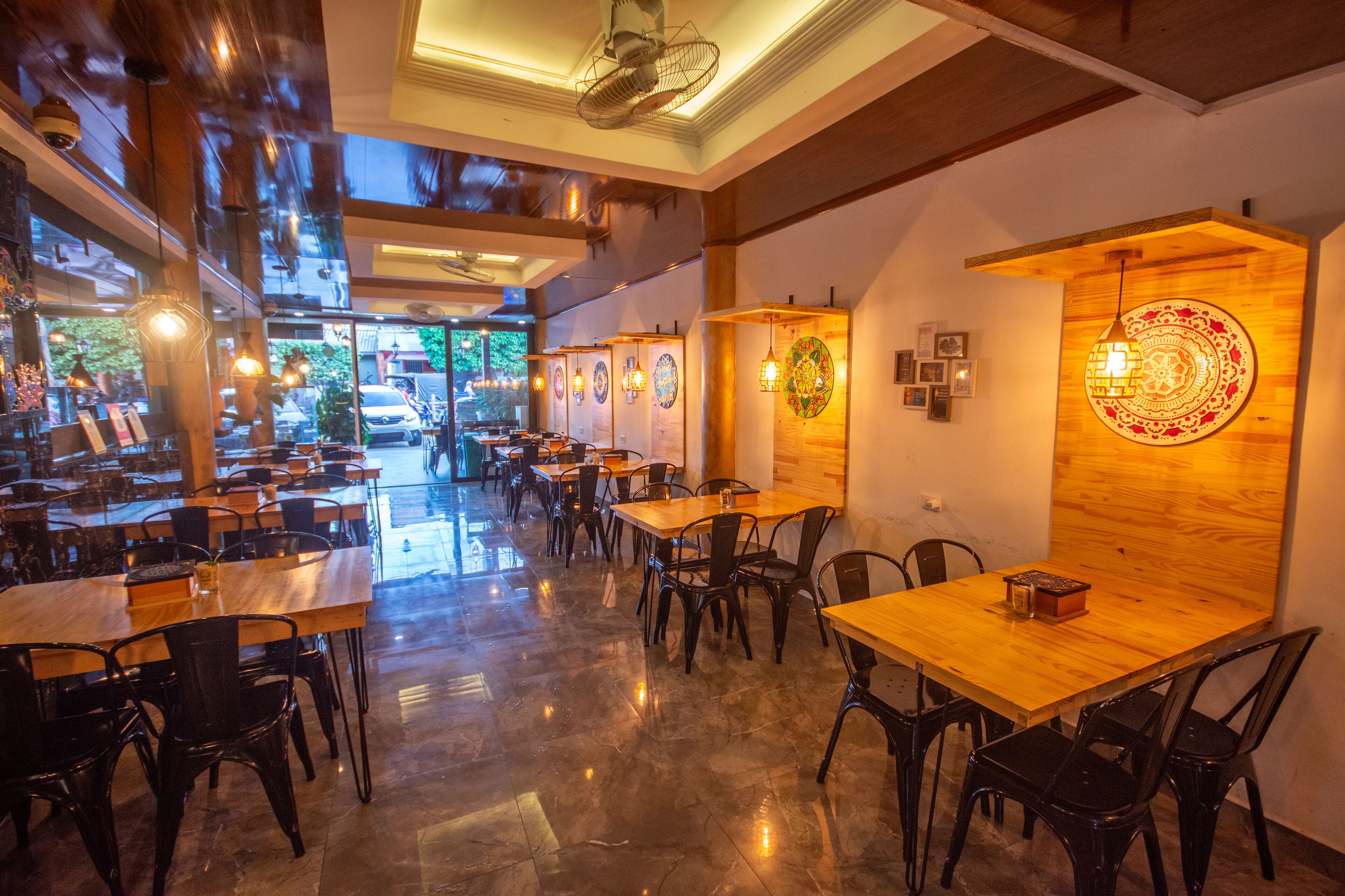 Un ampli restaurant amb taules i cadires de fusta, grans finestres i decoració mural.