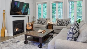 Un salon spacieux doté d’une cheminée, d’un téléviseur, d’un canapé et d’un ventilateur de plafond.
