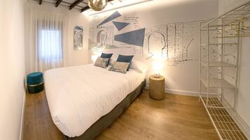 Una camera da letto con un letto grande, pavimento in legno, una mappa appesa al muro e una scaffalatura in metallo.