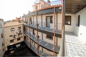 Un edificio de varios pisos con balcones, techo de tejas y un patio interior.