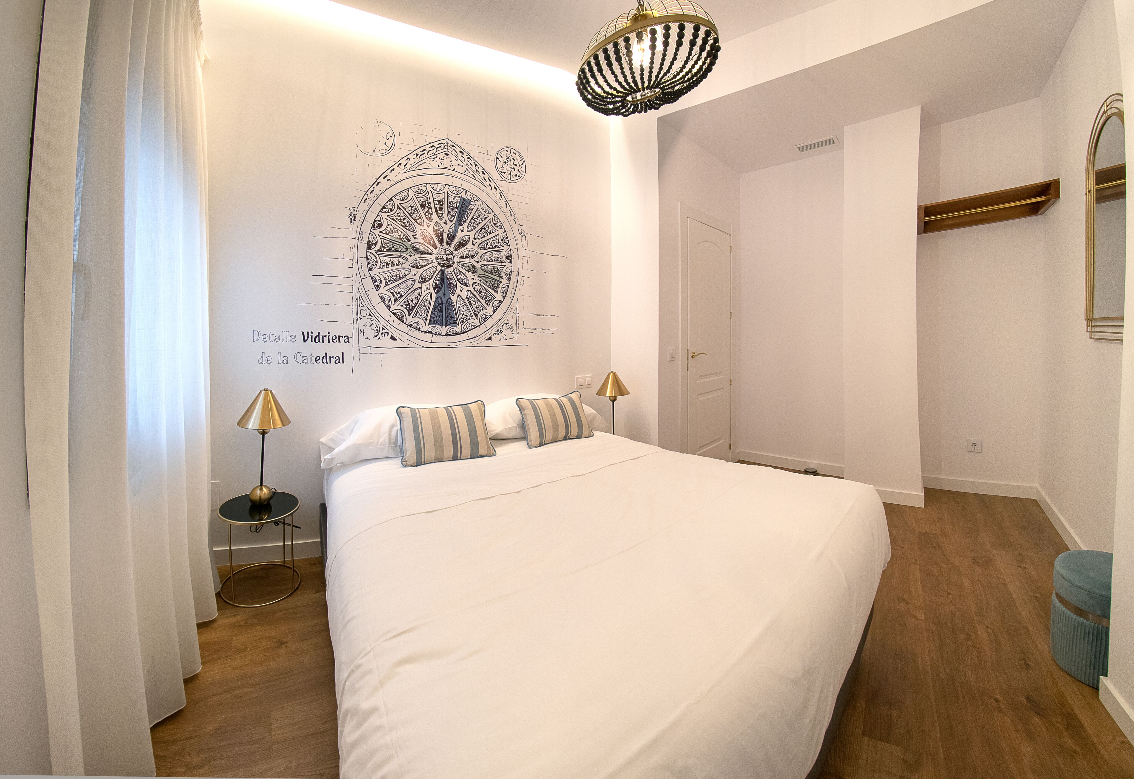 Un dormitorio con una cama grande, un mural en la pared, una araña y una puerta.