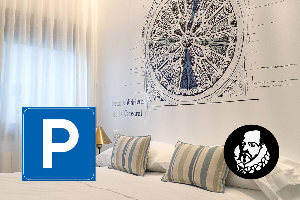 A hotel room with a large wall mural, a bed with striped pillows, and a chandelier.