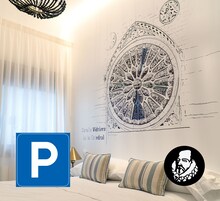 A hotel room with a large wall mural, a bed with striped pillows, and a chandelier.