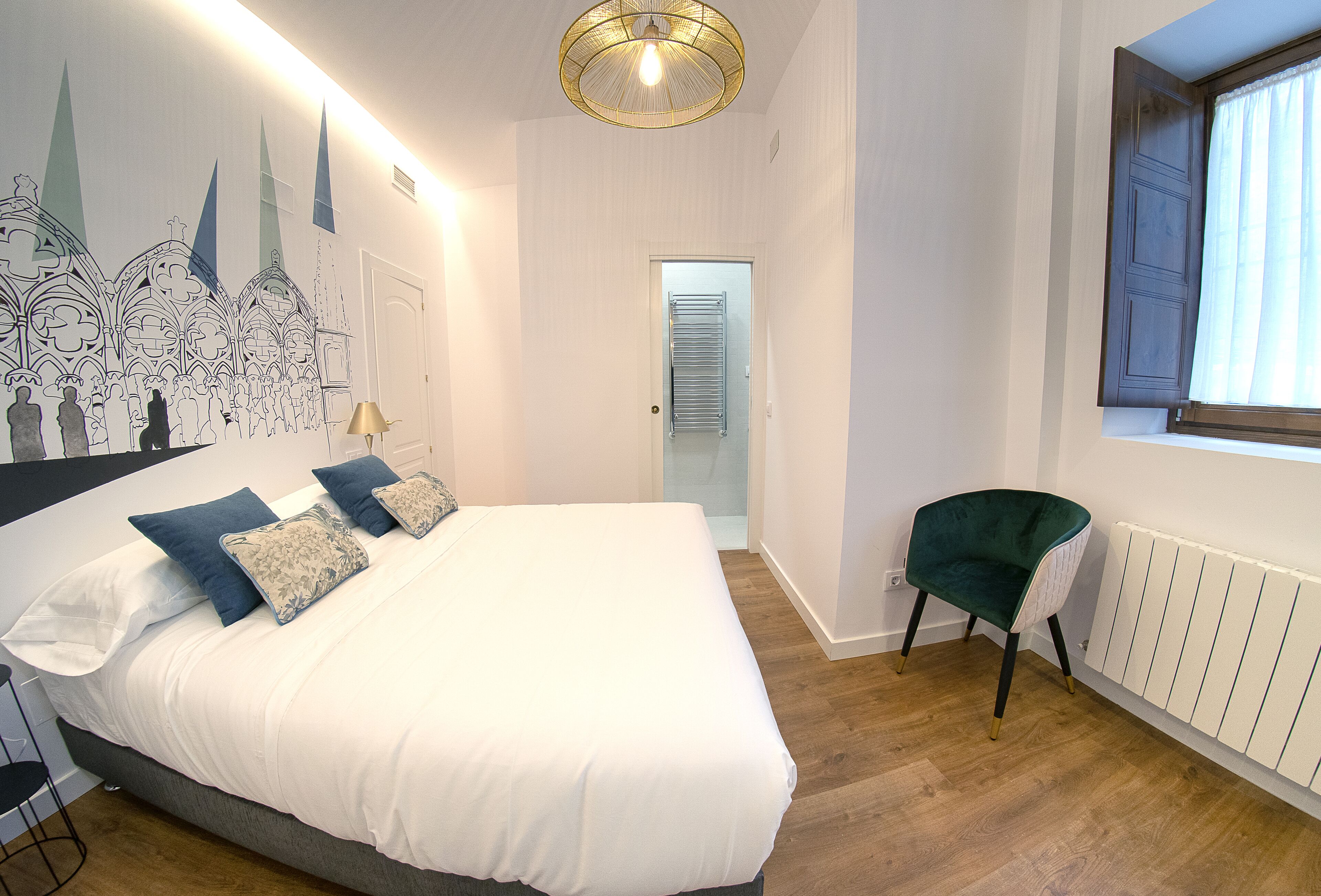 A bedroom with a large bed, a chair, a radiator, and a window.