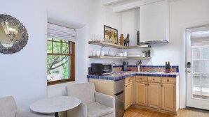 Une cuisine compacte avec un coin repas, des meubles en bois, un four à micro-ondes et une fenêtre donnant sur un espace verdoyant.