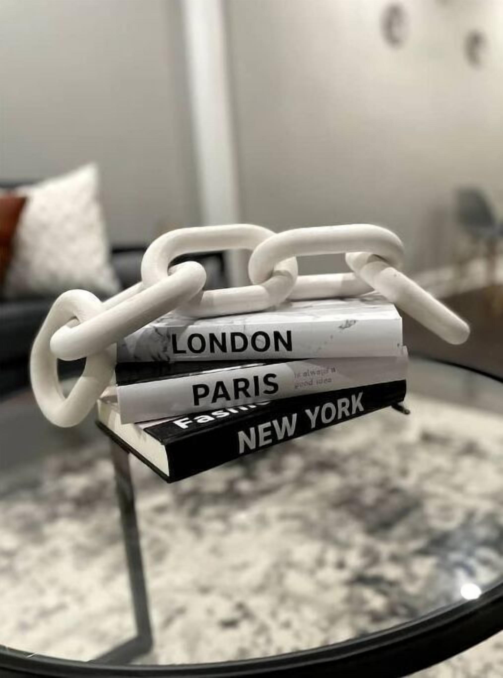A stack of books titled 'LONDON', 'PARIS', and 'NEW YORK' on a glass table.