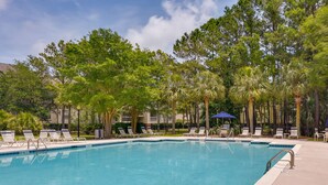 A swimming pool with lounge chairs and palm trees in the background.