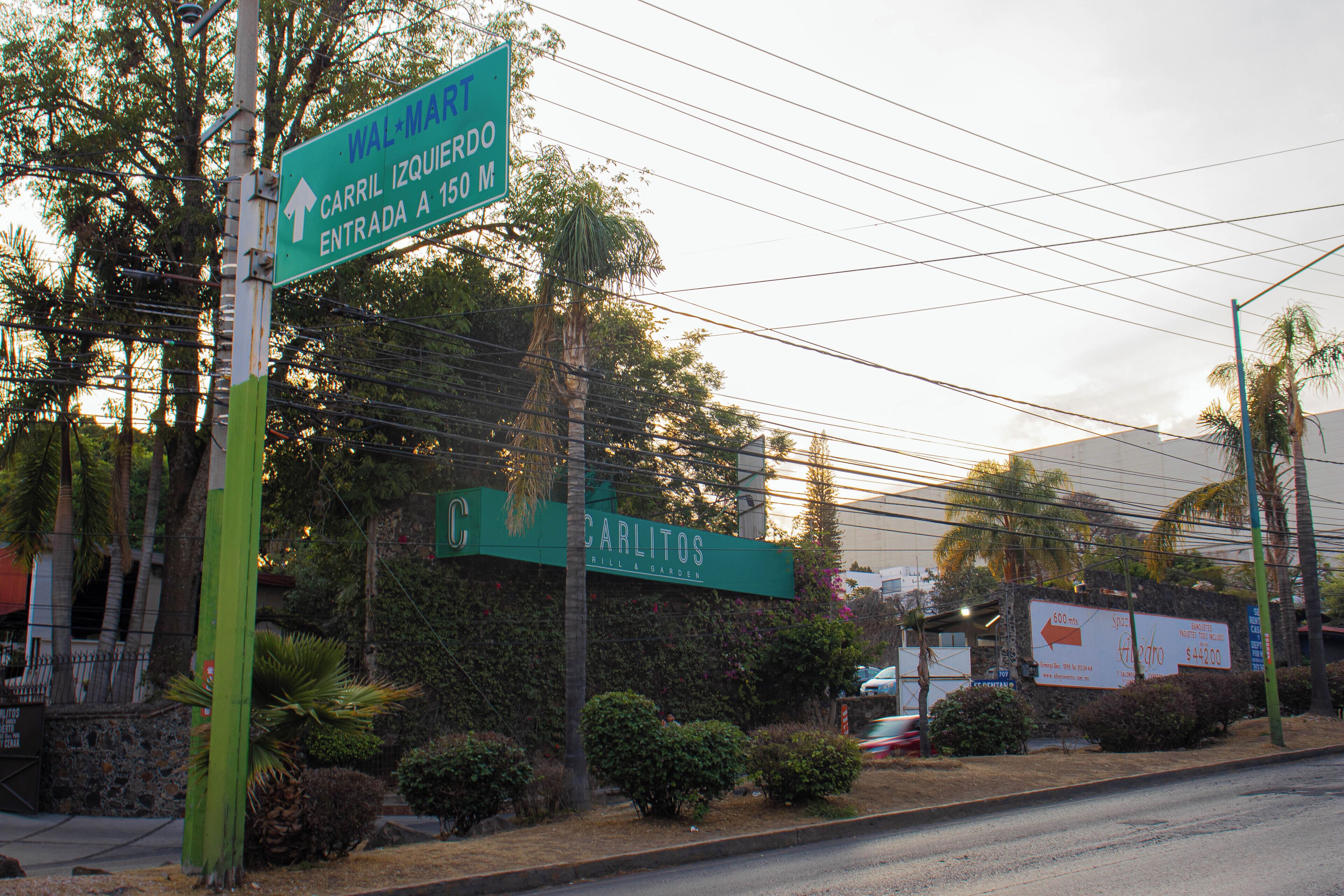 A street sign with directions to a mall and a restaurant.