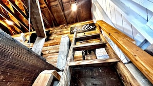 A wooden staircase with a 'hello' sign at the top, leading to a room with wooden walls and a sloped ceiling. - Tiny House Hideaway with King sized Bed (Cape Charles)