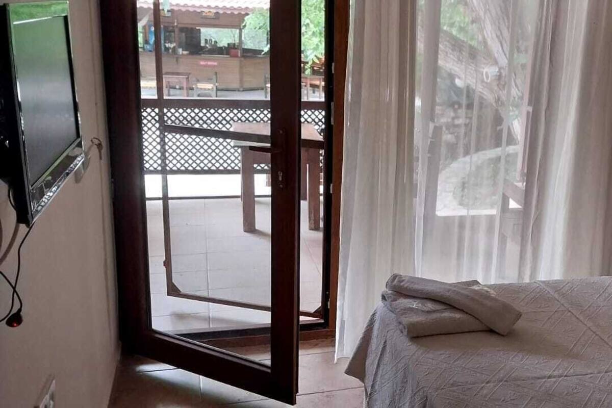Une chambre à coucher comprenant un lit, une table de chevet, un téléviseur fixé au mur et donnant sur le balcon extérieur.
