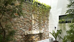 A stone wall with plants growing on it, a concrete bench, and potted plants on the ground. - Hotel Boutique Casa Marichu - Design Studio, Pool & Colonial Rooftop M1 (Ciudad de Panamá)