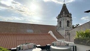 A rooftop terrace with two round seating areas, a view of a church tower, and a corrugated metal roof. - Hotel Boutique Casa Marichu - Design Studio with Pool and Rooftop M2 (Ciudad de Panamá)