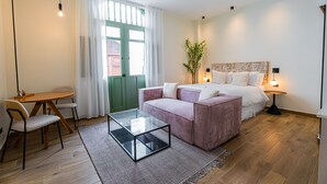 A modern bedroom with a bed, a sitting area with a table and chairs, a glass coffee table, and a large window with curtains. - Hotel Boutique Casa Marichu - Design Studio with Pool and Rooftop M2 (Ciudad de Panamá)