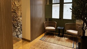 A cozy room with a stone wall, two wicker chairs, a small table, and a large window with shutters. - Hotel Boutique Casa Marichu - Design Apartment with Pool and Rooftop M4 (Ciudad de Panamá)