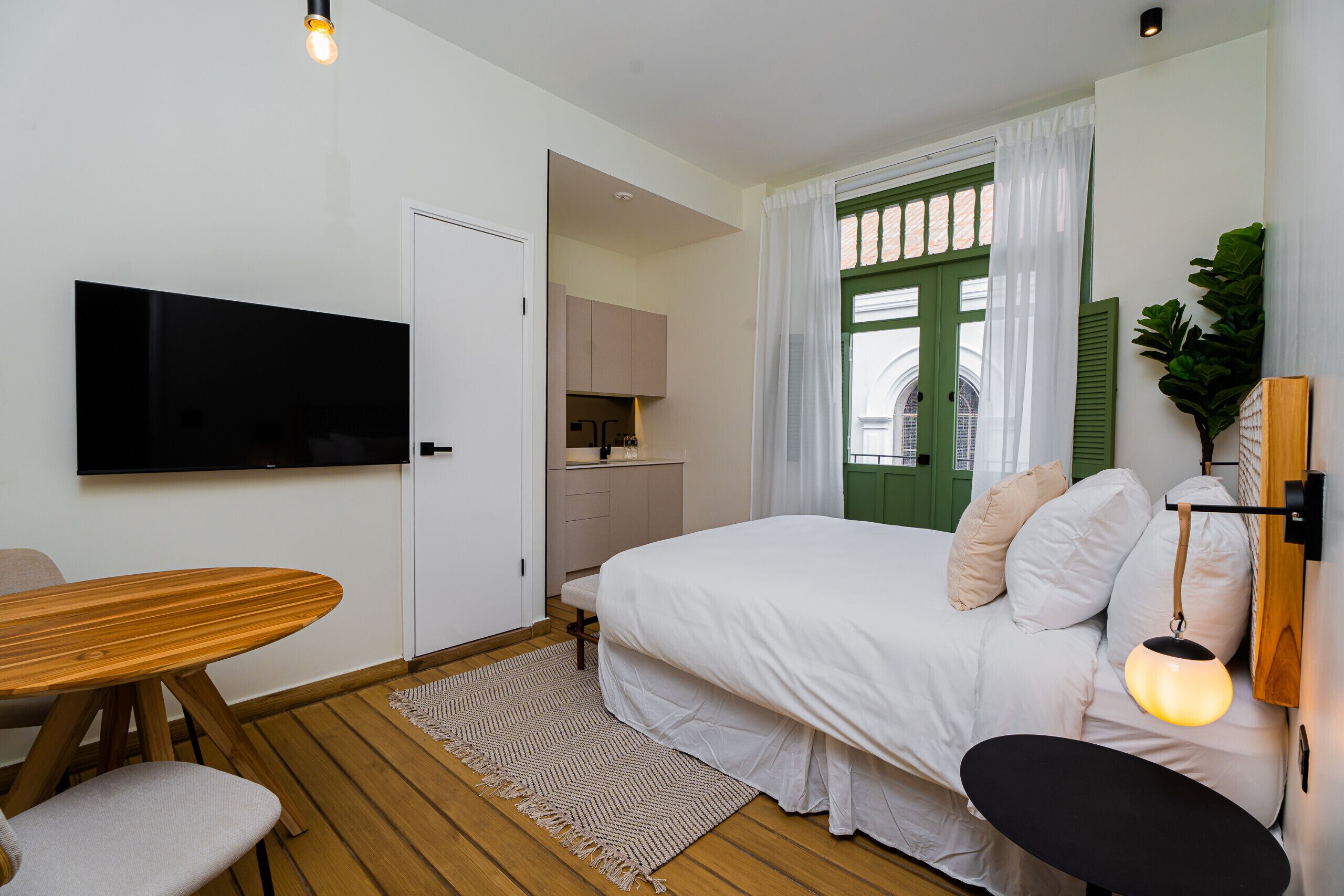 Une chambre à coucher avec un lit, un téléviseur fixé au mur, une table en bois et un banc.