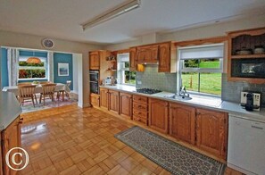 A kitchen with wooden cabinets, a dining area with a table and chairs, and a view of the outdoors.