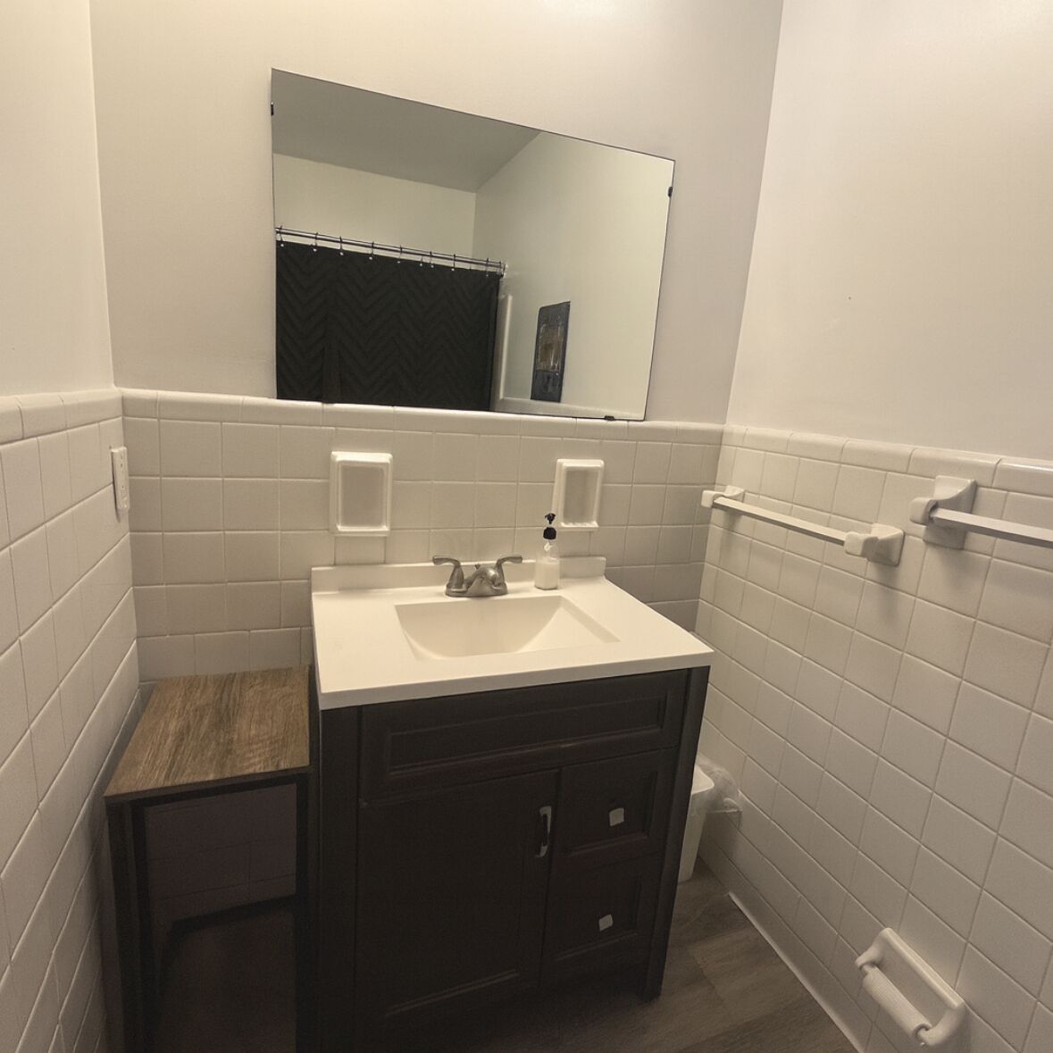 A bathroom with a white sink, dark cabinets, a mirror, and a shower curtain.