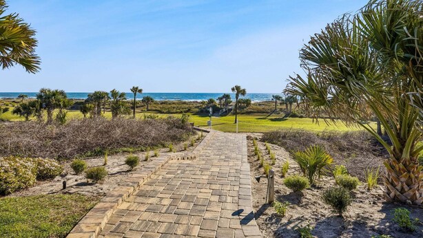 A paved pathway leading to a beach with palm trees and shrubs. - Heated Pool, Ocean Views, Pet-Friendly Paradise (Fernandina Beach)