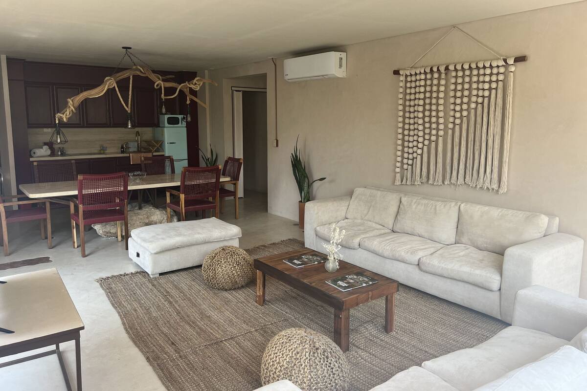 A living room with a sofa, coffee table, and dining area with chairs.