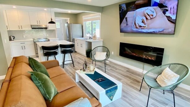 A modern living room with a brown sofa, a coffee table, and a TV mounted on the wall.