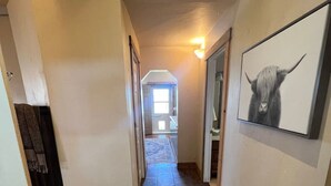 A hallway with a stone floor, a framed picture of a yak, and a door on the left. - Starlight Casita Durango (Durango)
