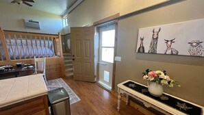 A kitchen with wooden cabinets, a countertop, a trash can, a bench, and a door leading to another room. - Starlight Casita Durango (Durango)