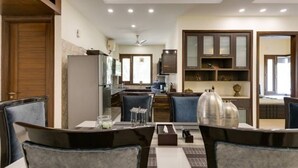 A modern kitchen with built-in appliances, a dining area with a table and chairs, and a living area with a sofa and decorative items. - Cozy Getaway: Clean and modern!!!    Breakfast Included !! (Gurugram)