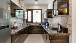 A modern kitchen with dark wood cabinets, stainless steel appliances, and a tiled backsplash. - Cozy Getaway: Clean and modern!!!    Breakfast Included !! (Gurugram)