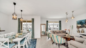Een moderne woonkamer met een bank, salontafel en een eethoek met stoelen en een tafel.