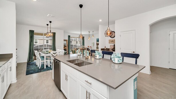 Een moderne keuken met een centraal eiland, witte kastjes en hanglampen.