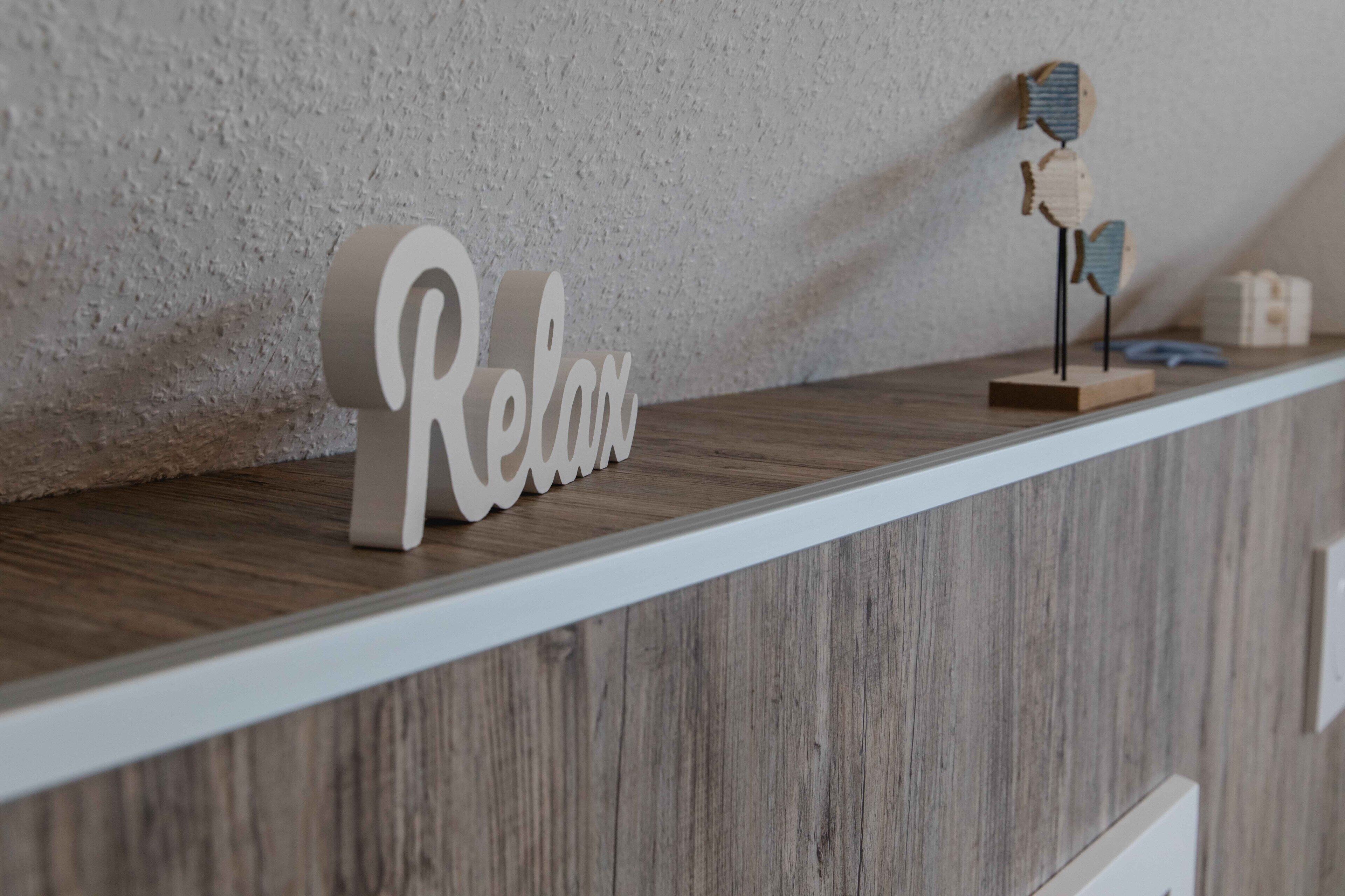 A wooden shelf with a 'Relax' sign and a decorative wooden sculpture.