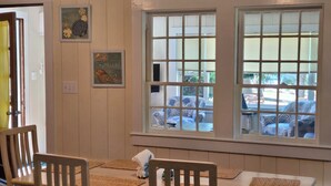 Ein Essbereich mit Holztisch und -stühlen, einem Fenster mit Jalousien und Wandbildern.