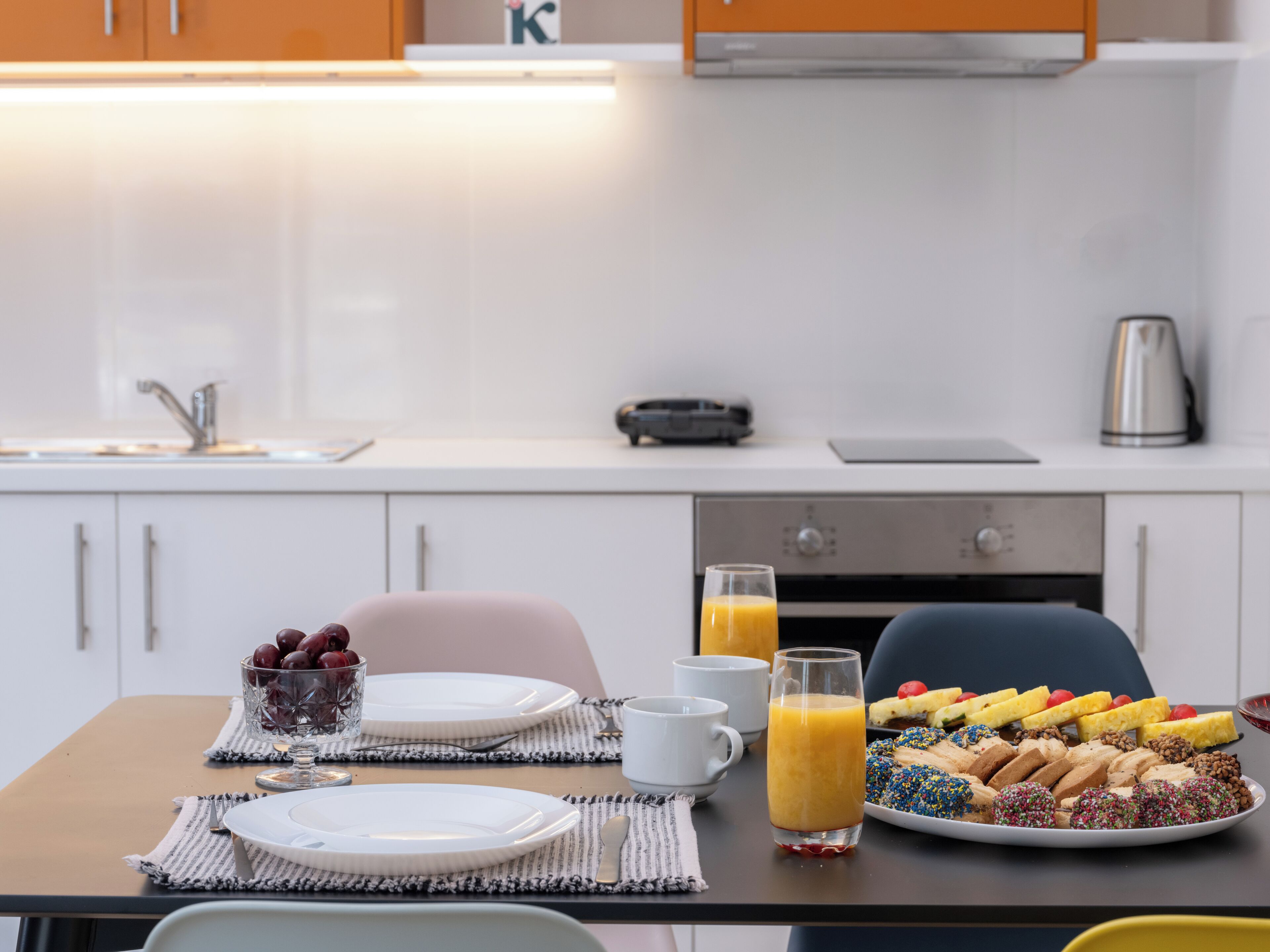 Una mesa con platos, vasos y una variedad de bollería y frutas para el desayuno.