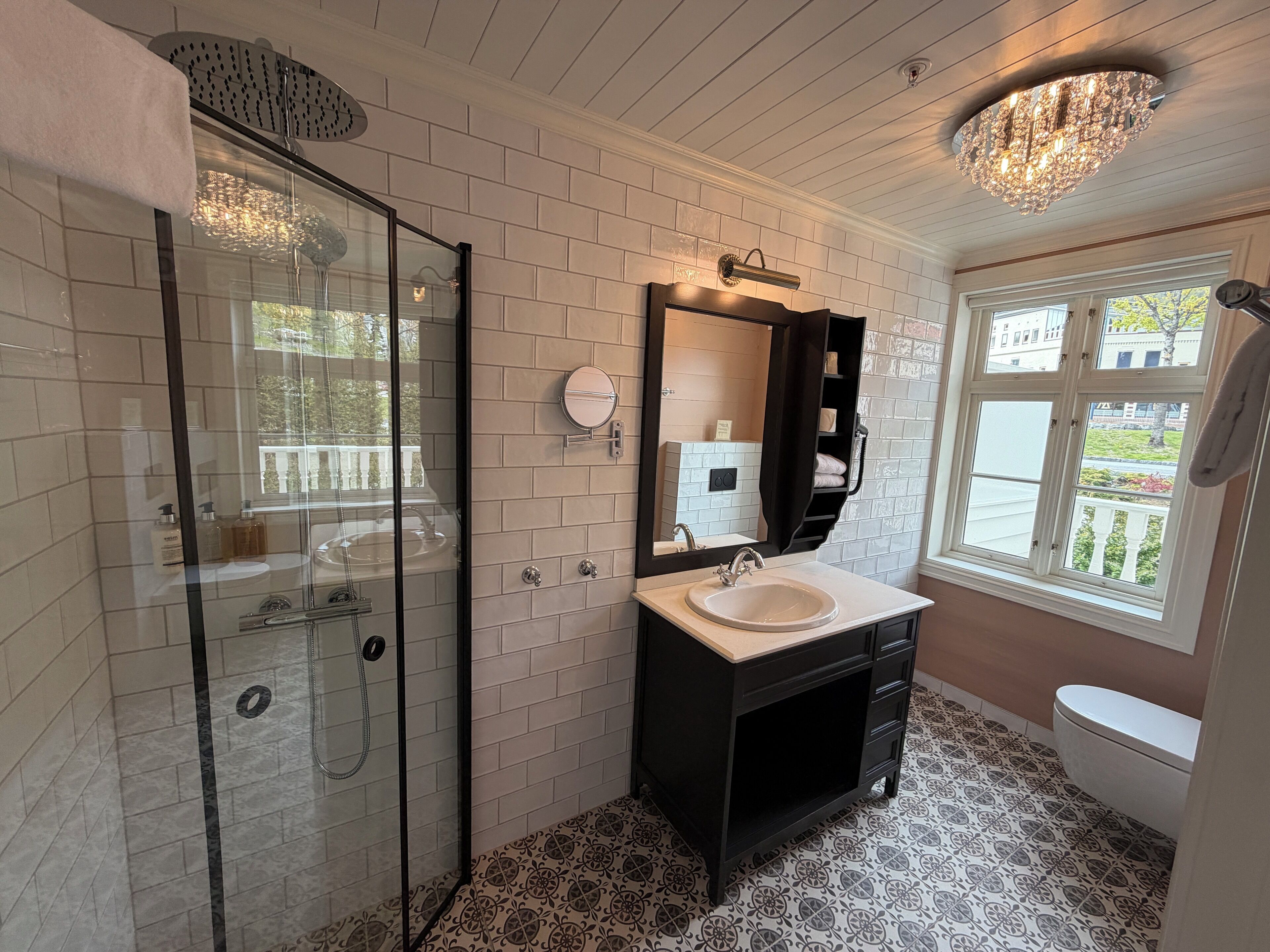 Une salle de bain avec une douche à parois de verre, un lavabo avec un miroir et des toilettes.