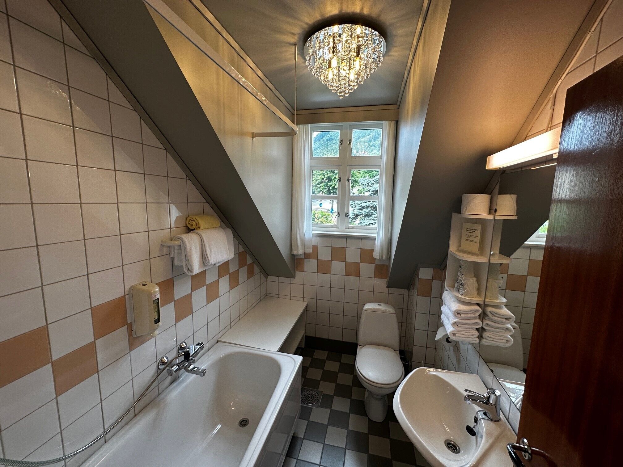 Un baño con bañera, lavamanos, inodoro, candelabro y ventana.