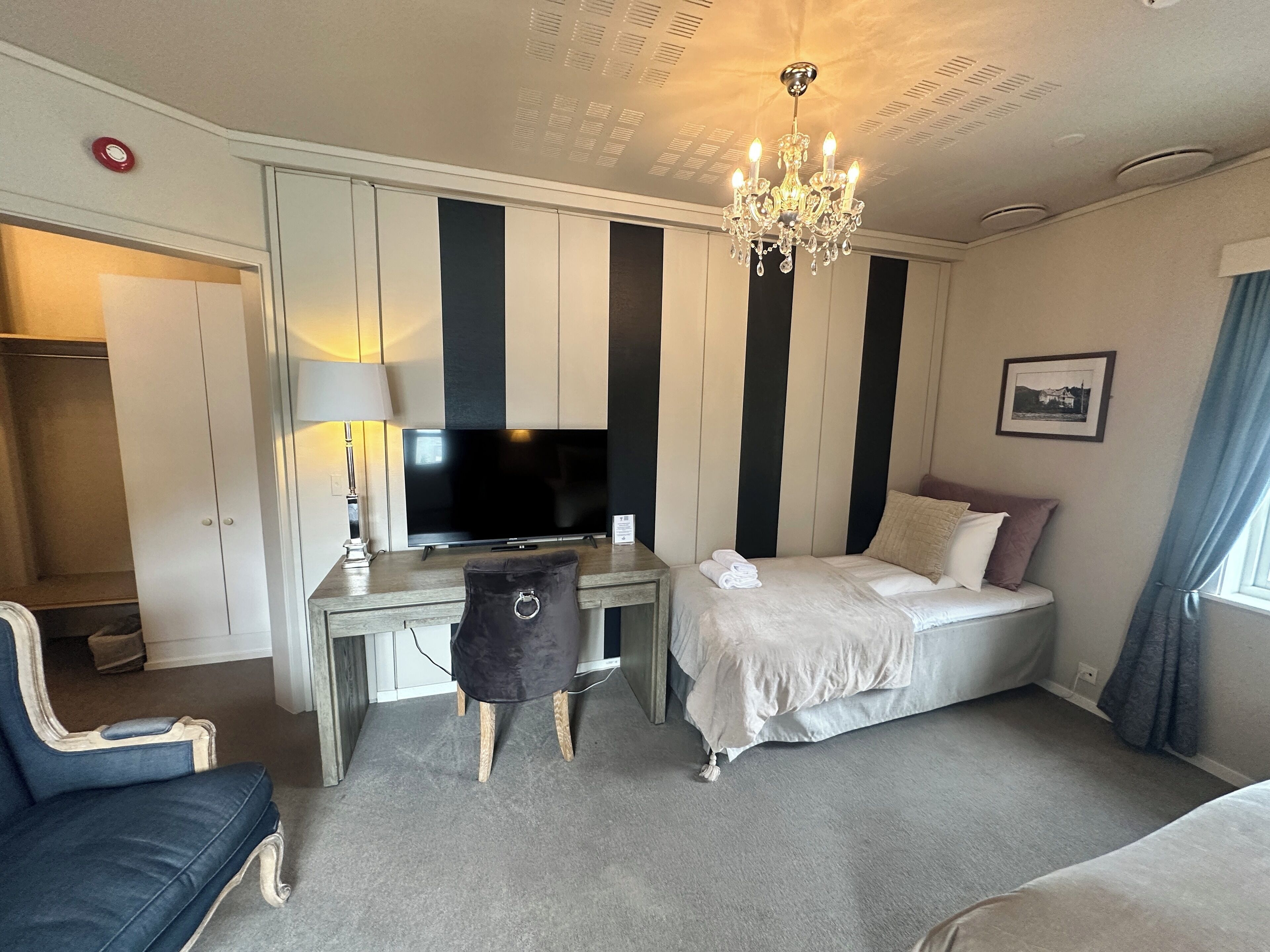 Une chambre d’hôtel comprenant un lit, un bureau avec une télévision, une chaise et une armoire.