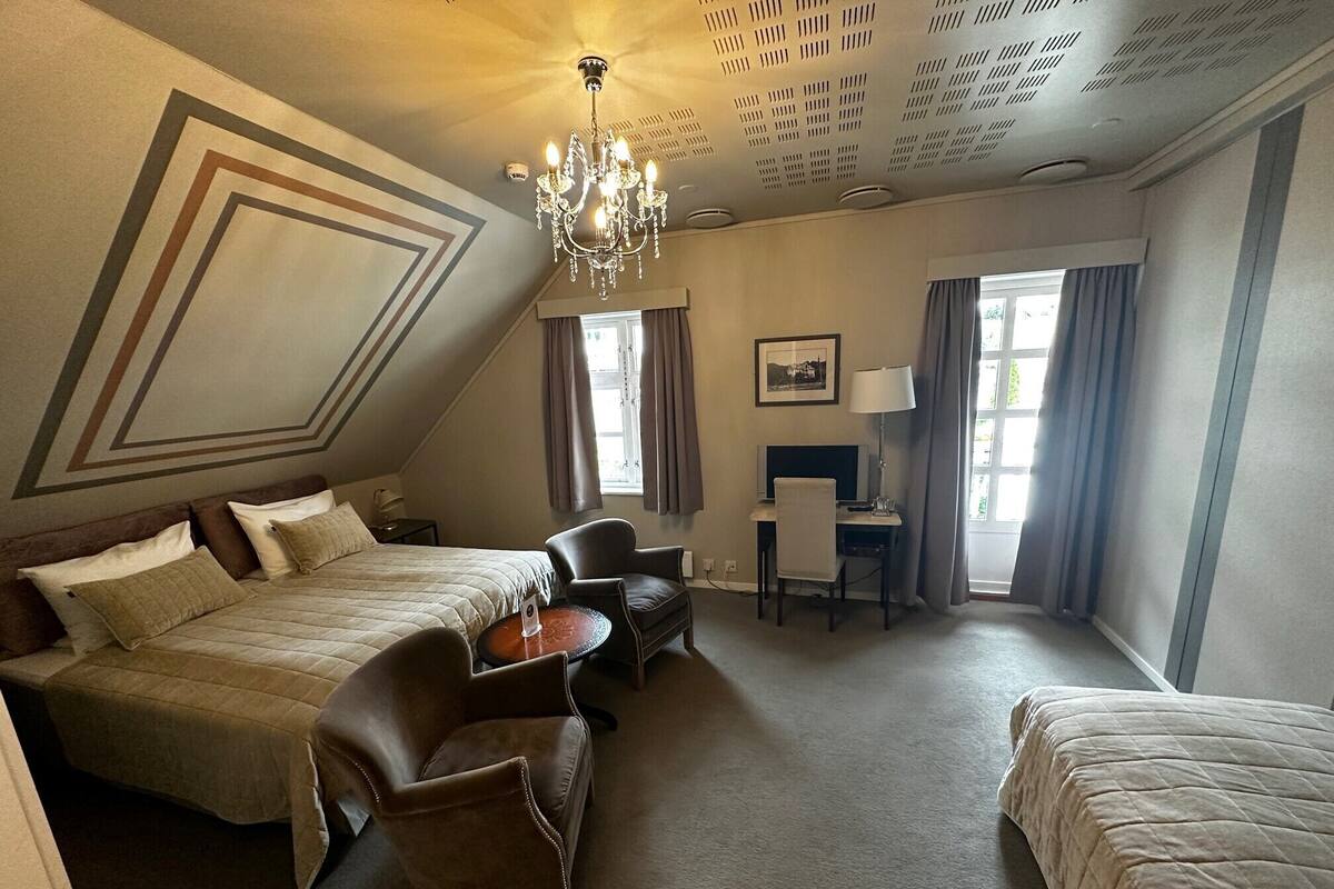Una habitación de hotel con cama, escritorio, silla y candelabro.