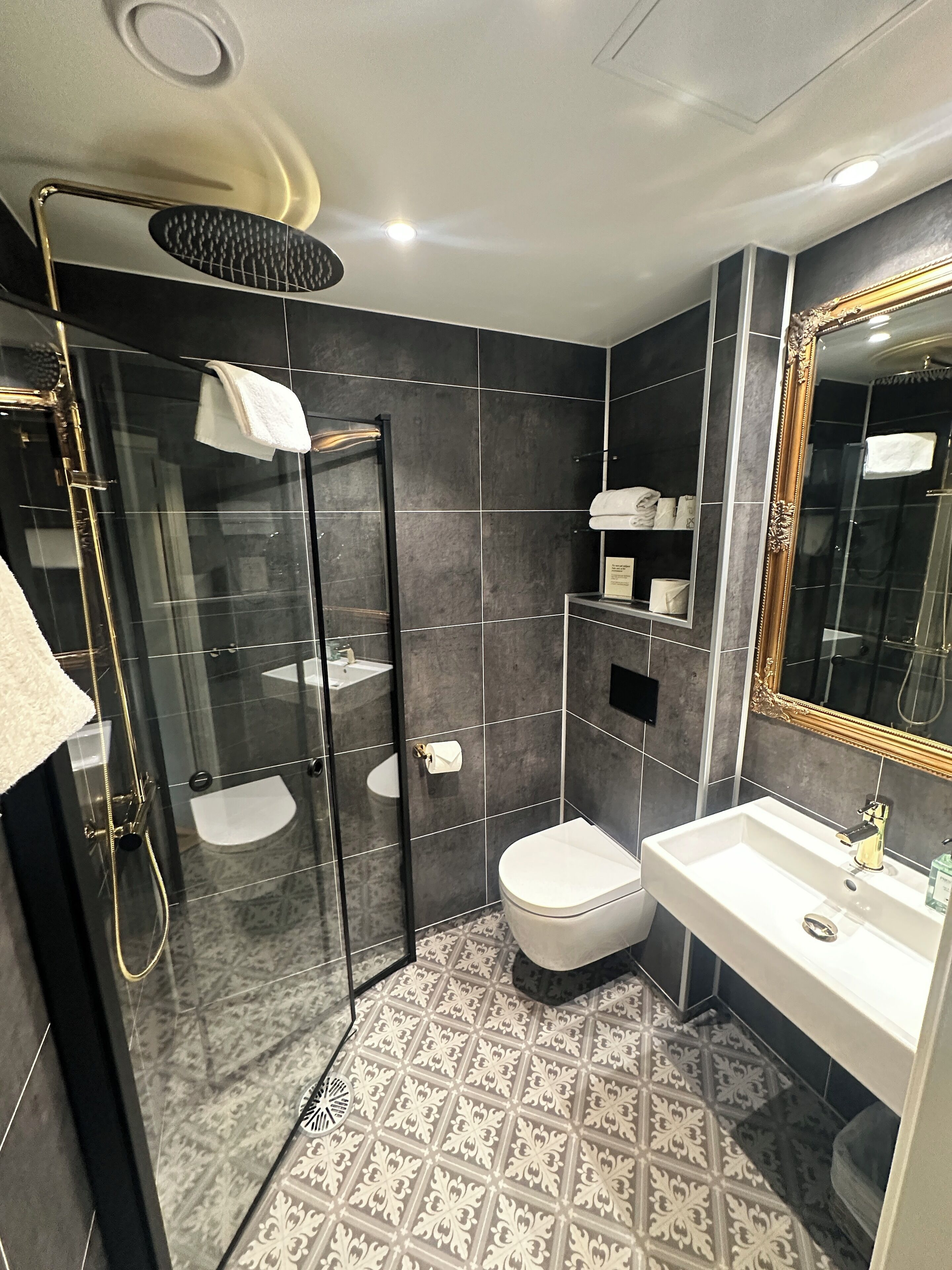 A modern bathroom with a glass-enclosed shower, a white sink, and a large mirror.