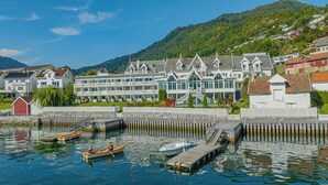 A waterfront hotel with multiple balconies, a dock, and a mountain backdrop.