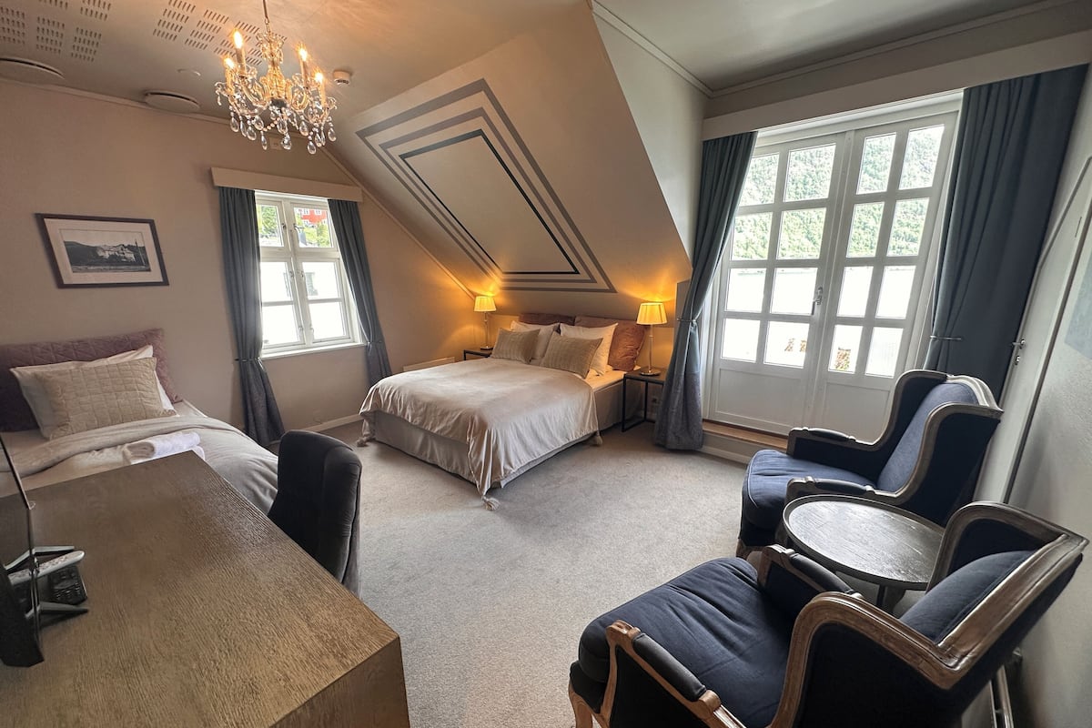 Una habitación de hotel con cama, escritorio, silla y una mesita.